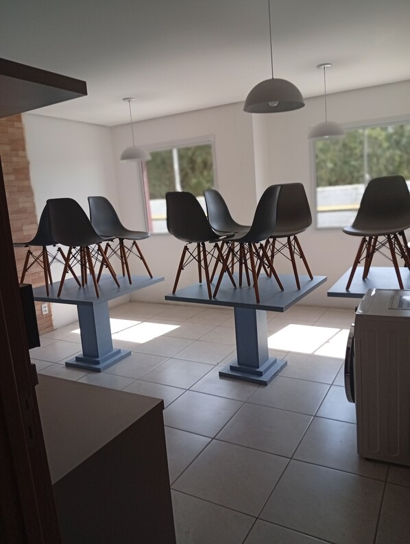A modern interior with tables and chairs, large windows, and a ceiling light fixture.