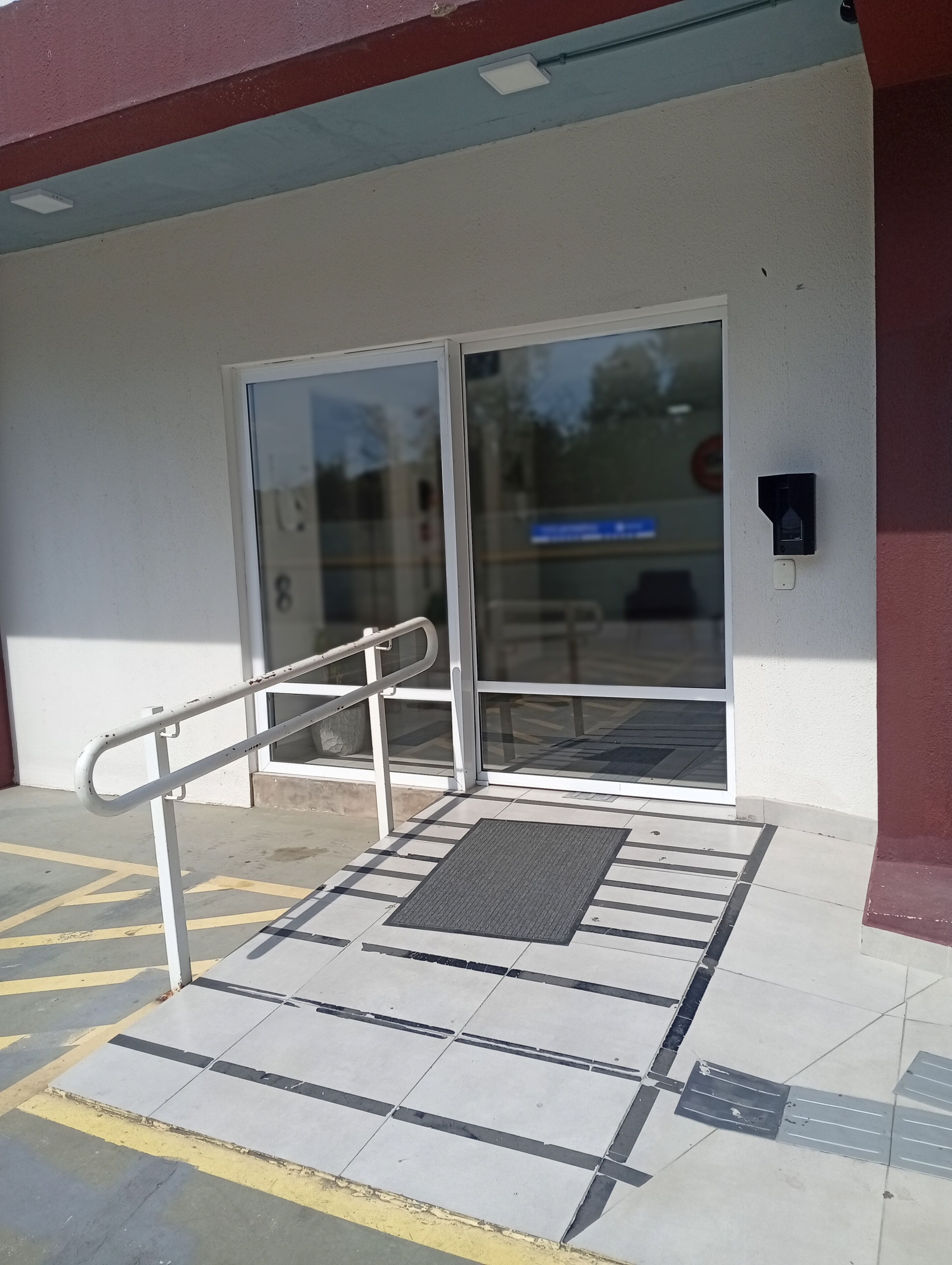 Ingresso di un edificio con rampa, porta e superficie tattile.