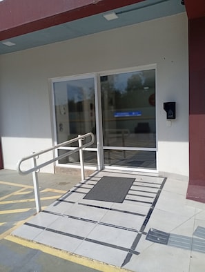 A building entrance with a ramp, a door, and a tactile paving surface.