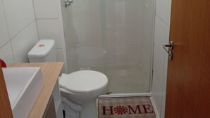 Une petite salle de bain comprenant des toilettes, un espace douche et une porte en bois.
