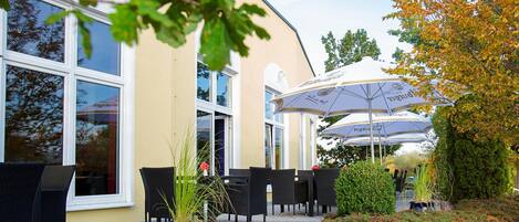 Un espace extérieur aménagé avec des tables et des chaises, un pot de fleurs et des parasols.