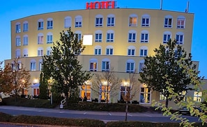 Een hotelgebouw met meerdere verdiepingen, een vlakke gevel, veel ramen en een groot bord met de tekst 'HOTEL' bovenaan.