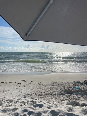 Eine Strandansicht mit blauem Himmel, Wellen und einem sandigen Ufer.