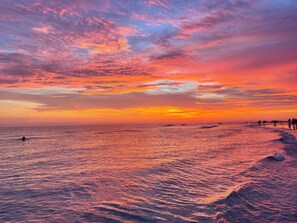 Ein Strand mit Wellen und einem Sonnenuntergang.