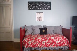 A bedroom with a red bedspread, checkered pillows, a black and white wall decor, and a framed picture of Paris. - The Caldwell House | Historic 1907 Estate (Abbeville)