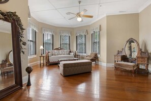 A spacious bedroom with a large bed, a sitting area, and a vanity with a mirror.
