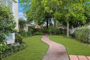 A well-maintained garden with a curved brick pathway leading to a house.