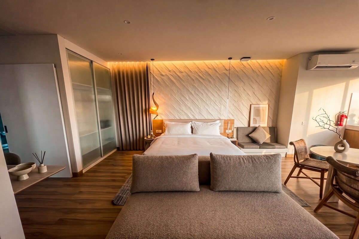 Une chambre moderne avec un grand lit, un canapé, un bureau et un coin repas.