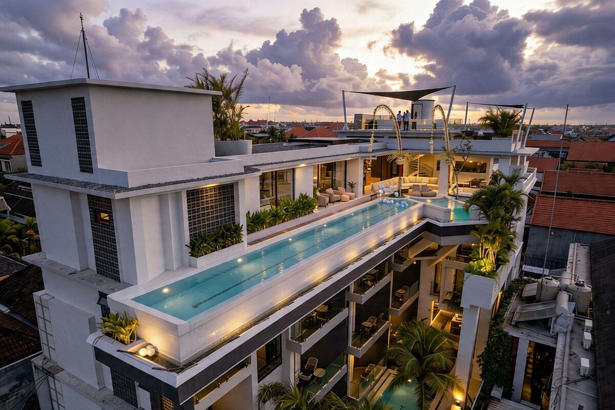 Un immeuble moderne à plusieurs étages, doté d’une piscine sur le toit, d’un espace extérieur aménagé et offrant une vue sur le paysage urbain.