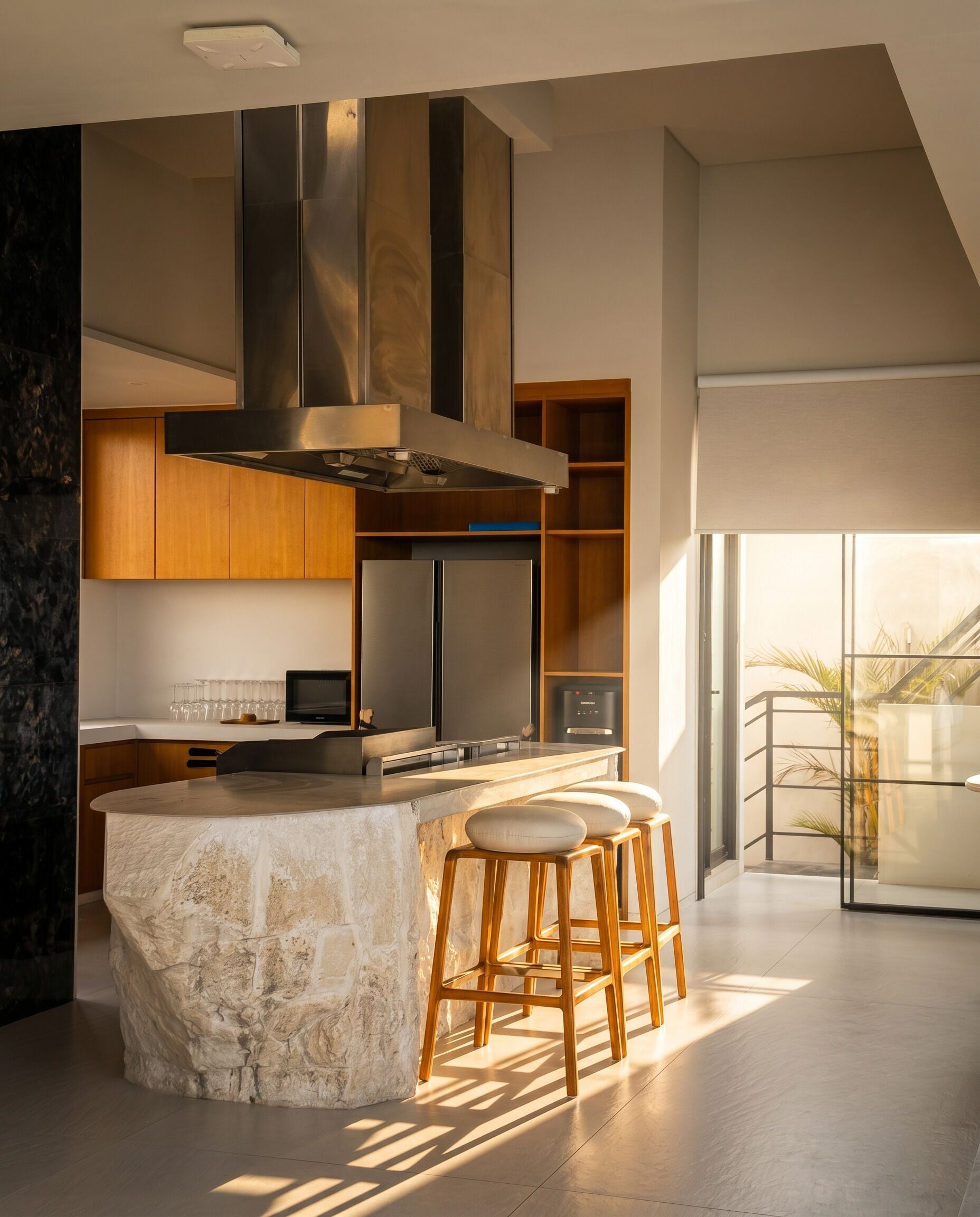 A modern kitchen with a stone island, stainless steel appliances, and wooden bar stools.
