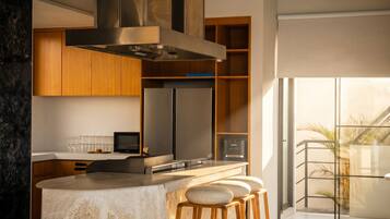 A modern kitchen with a stone island, stainless steel appliances, and wooden bar stools.