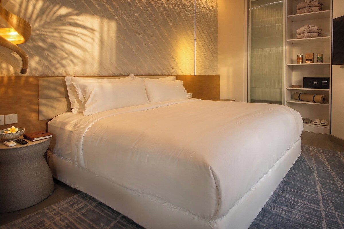 Une chambre d’hôtel comprenant un lit, une table de chevet, une lampe, une télévision et une armoire.