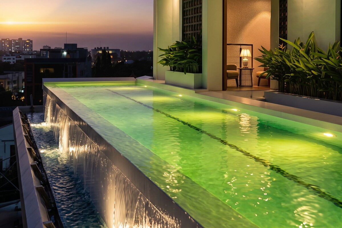 Un edificio moderno con piscina infinita en la azotea y una cascada.