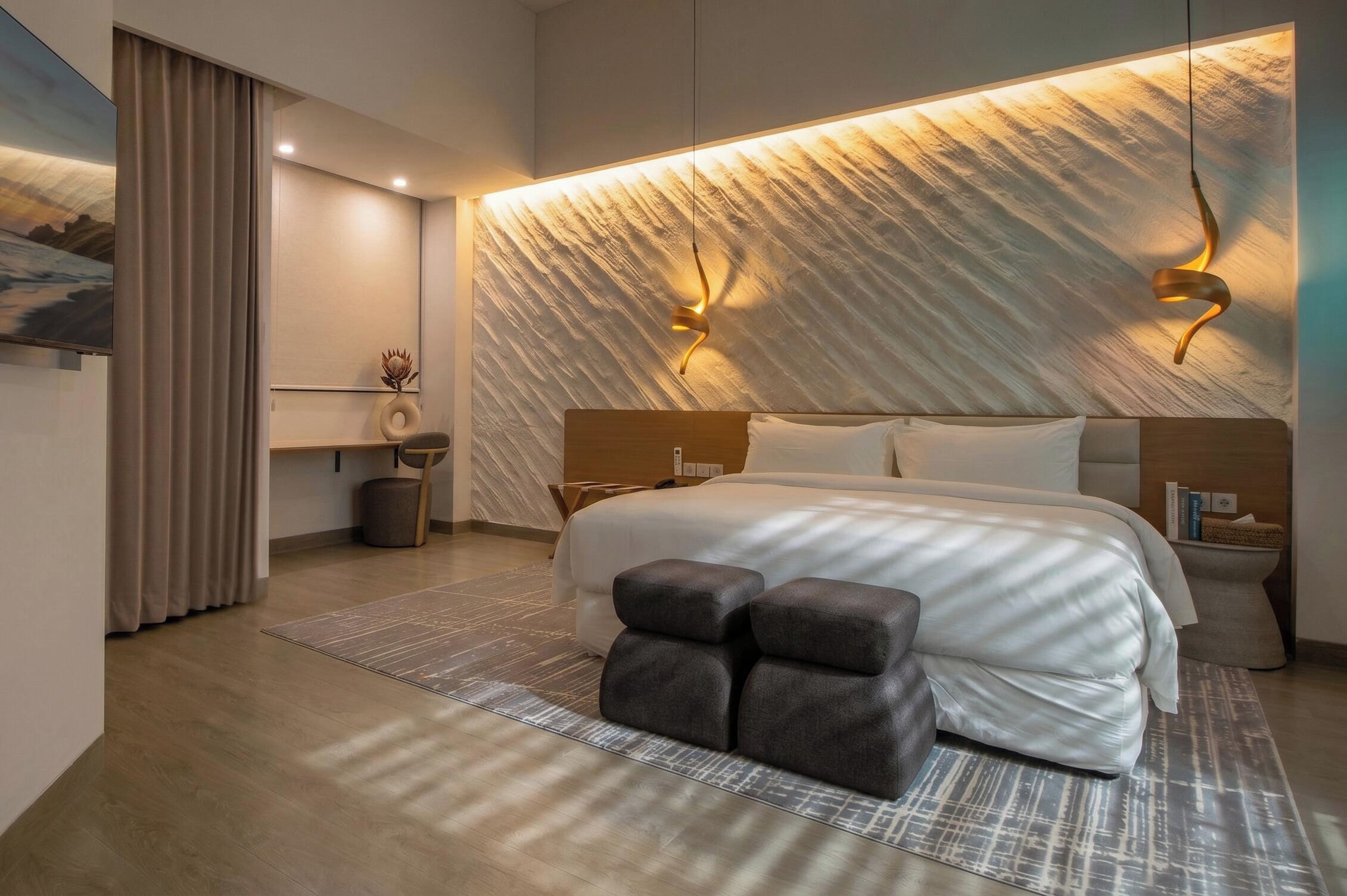 Un dormitorio moderno con una cama grande, cabecera con iluminación integrada, una mesita de noche y una obra de arte colgada en la pared.