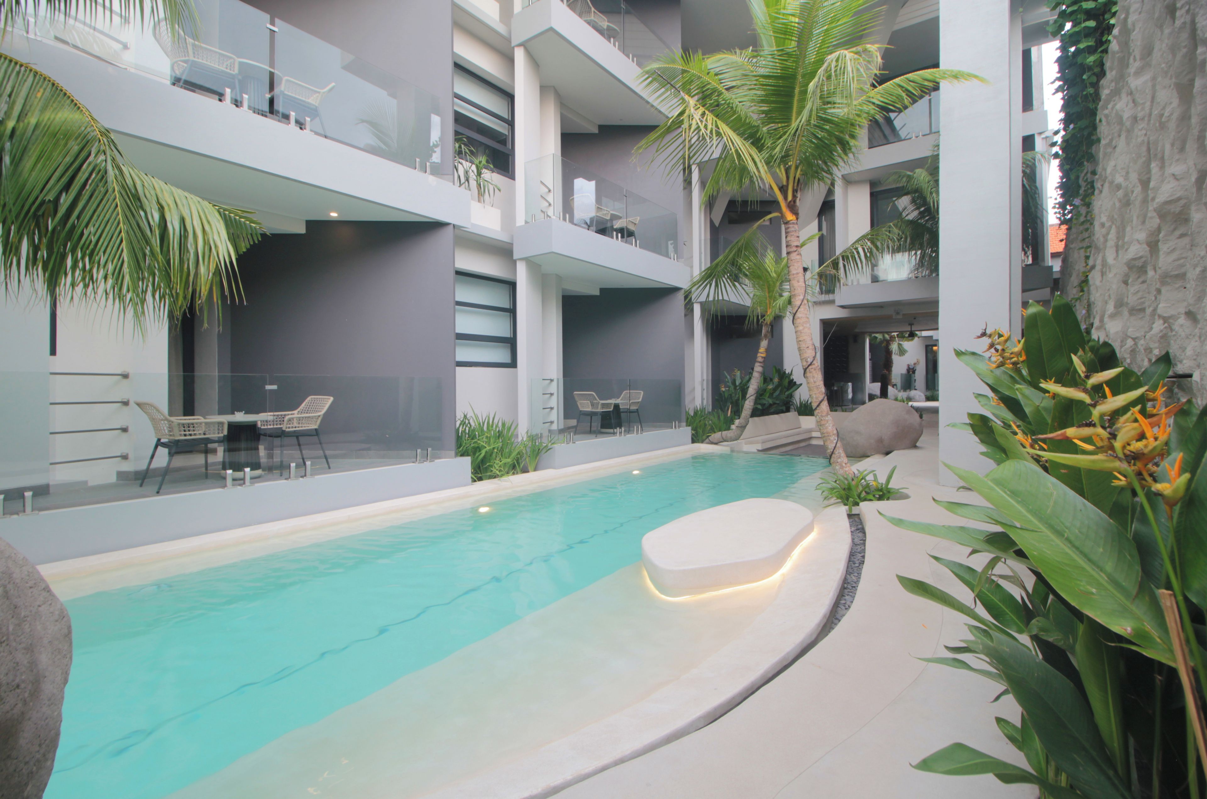 Une piscine intérieure moderne, avec une eau cristalline, entourée de chaises longues et de plantes en pot.