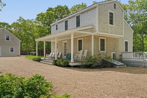 A two-story house with a covered porch and a gravel driveway. - Beach, Shop, Restaurants, Bike Path: 4 Min. to Town! Bikes & Beach Gear Included (Edgartown)