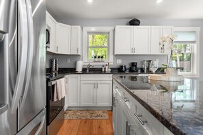 A modern kitchen with white cabinets, stainless steel appliances, and a granite countertop. - Beach, Shop, Restaurants, Bike Path: 4 Min. to Town! Bikes & Beach Gear Included (Edgartown)