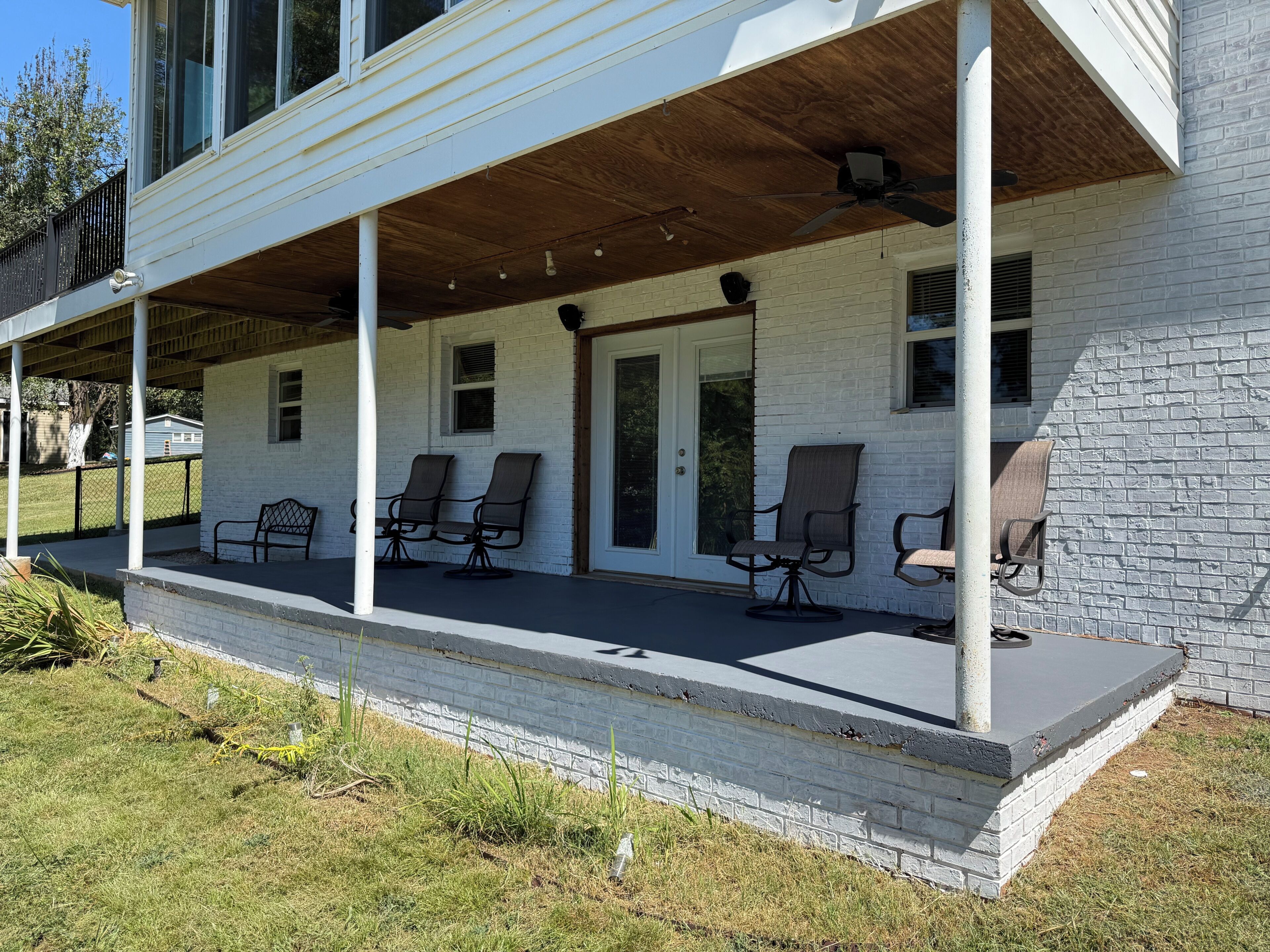 Een overdekte veranda met vier stoelen en een deur.