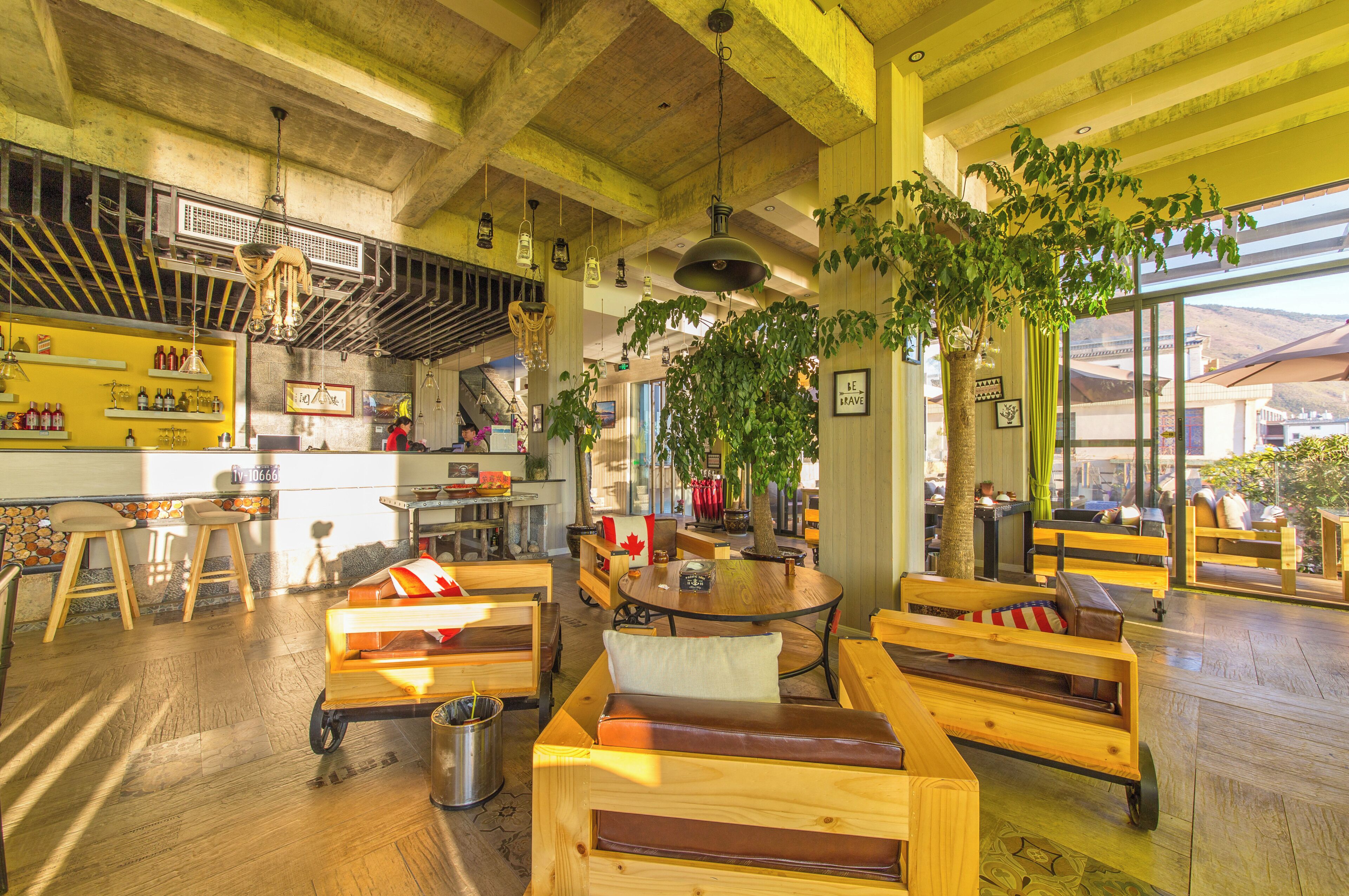 Un café acogedor con mobiliario de madera, una zona de bar y amplios ventanales que dejan entrar luz natural.