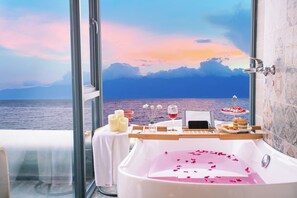 A bathroom with a bathtub filled with water, a table with candles, a glass of red wine, and a tray with snacks. - LS Inn Dali Liangsu Lake View (Dali)