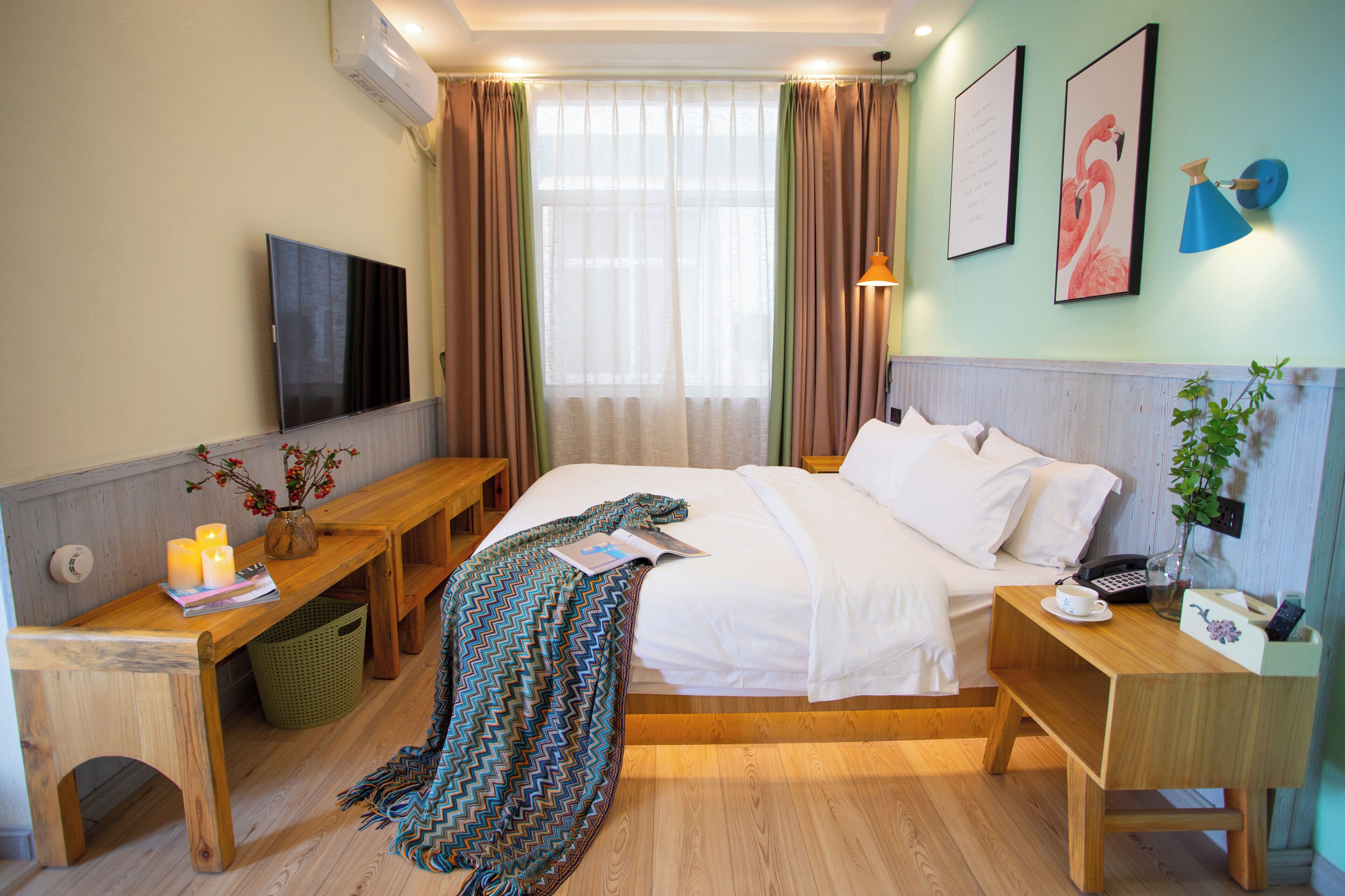 Ein Hotelzimmer mit Bett, Nachttisch, Fernseher und einem Fenster mit Vorhängen.