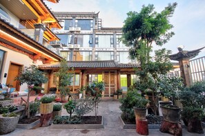 A traditional courtyard with potted plants, a wooden gate, and a building with a tiled roof. - LS Inn Dali Liangsu Lake View (Dali)