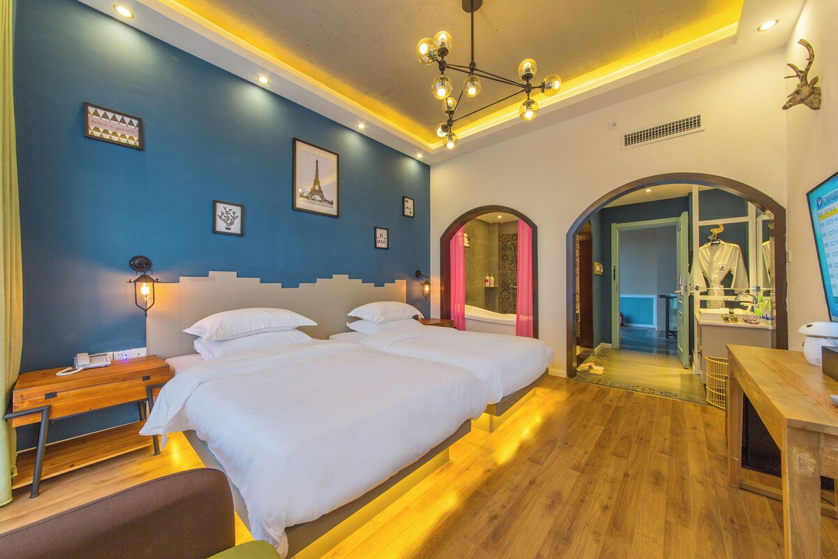 A hotel room with a bed, bedside table, lamp, and a mirror.