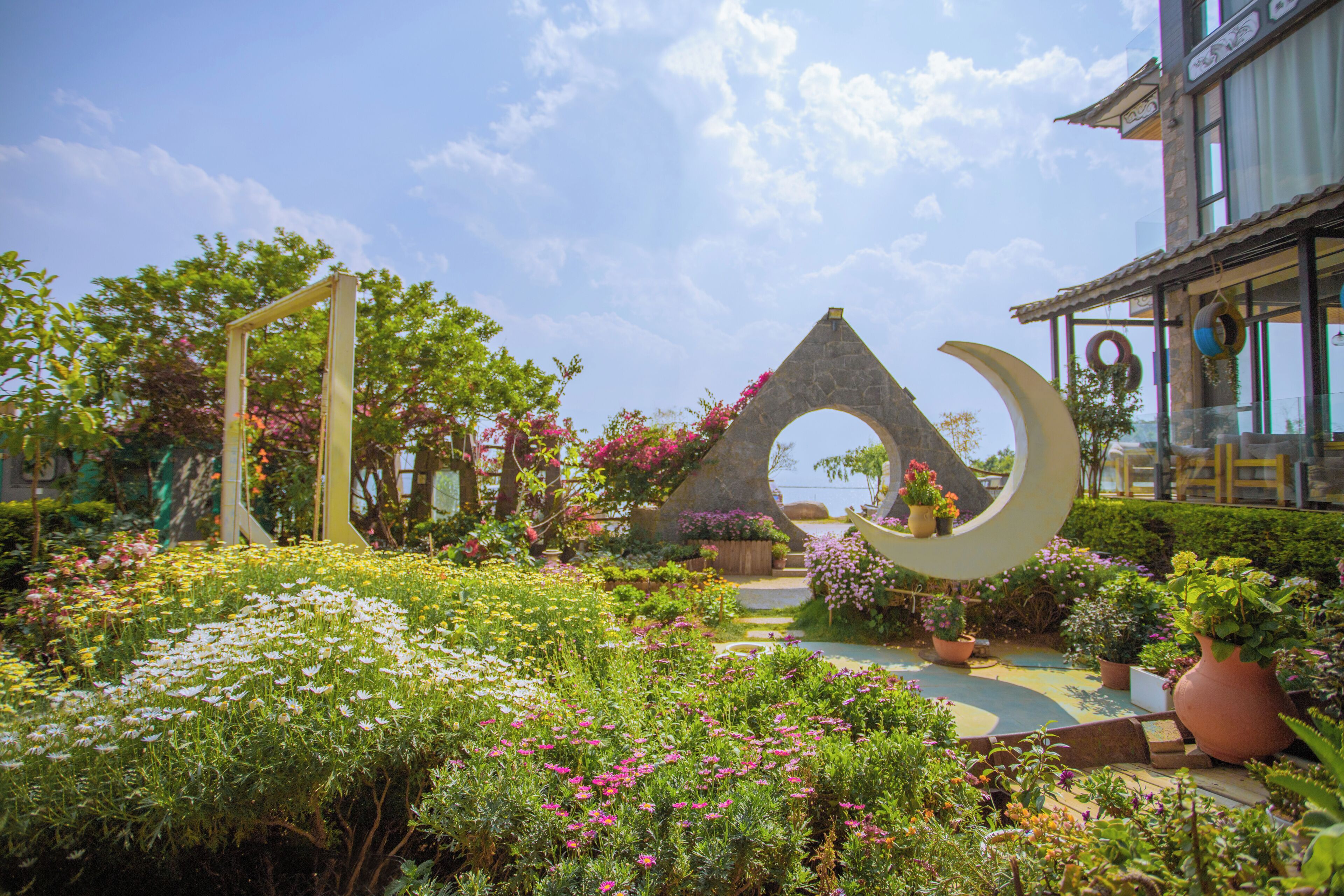 Un jardín con un gran arco, plantas en macetas y un sendero.