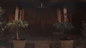 Un edificio tradicional con techo de tejas y puertas de madera, con plantas en macetas al frente.