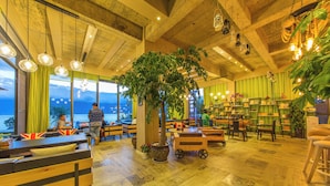 Un interior acogedor con muebles de madera, un gran árbol y vistas al exterior.