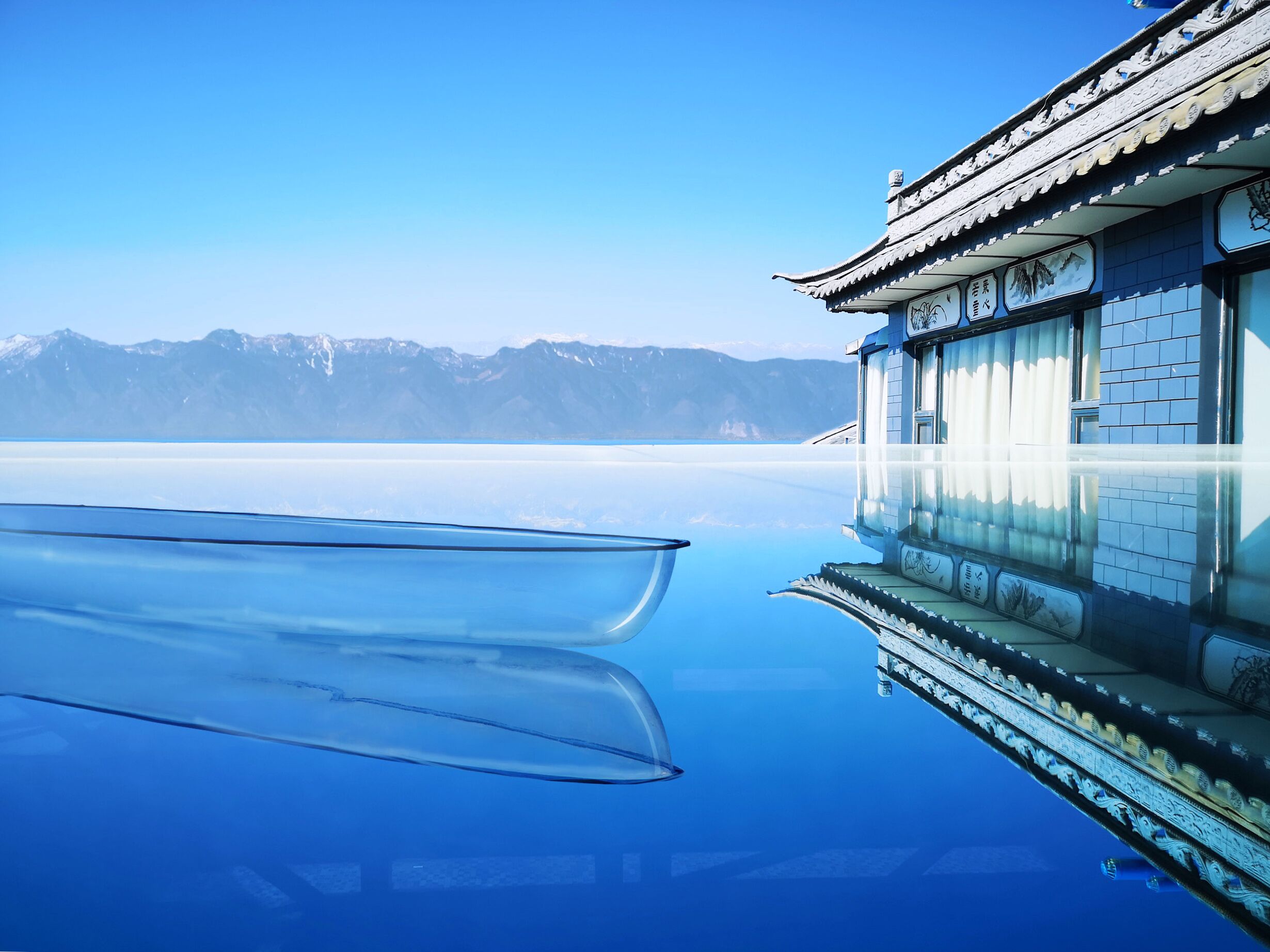 Un edificio tradicional con una piscina reflectante y vistas a montañas.