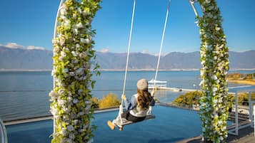 Una persona en una silla colgante con vista a un lago y montañas.