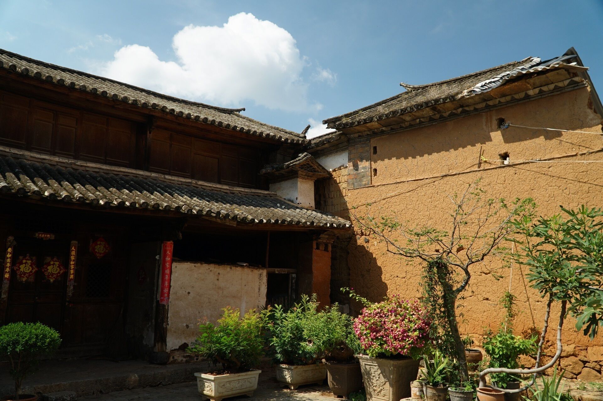 Un bâtiment traditionnel avec un toit en tuiles et une cour intérieure agrémentée de plantes en pot.