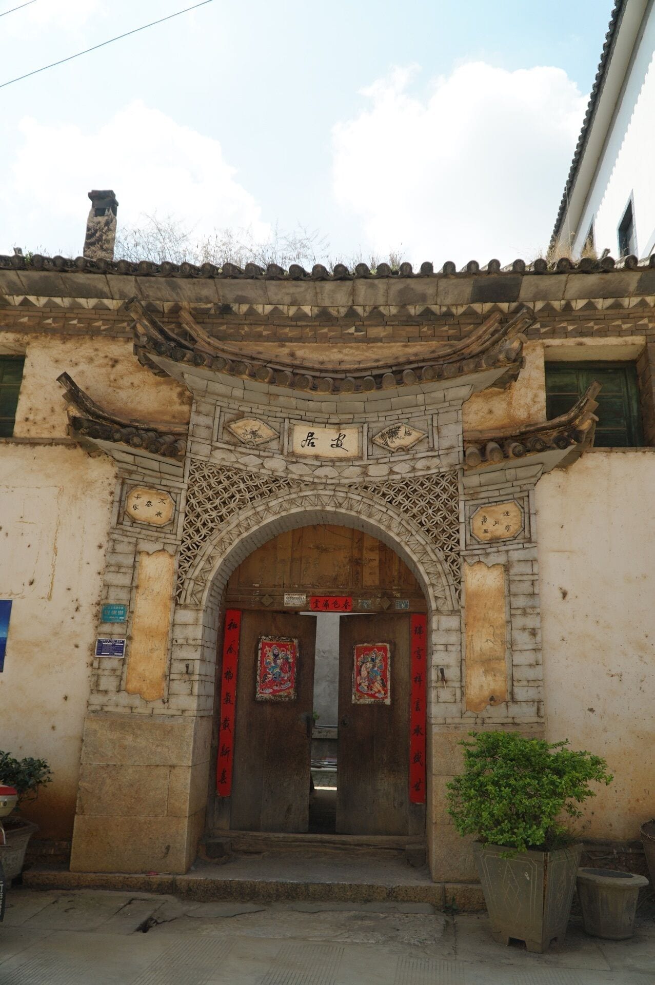 Un edificio tradicional con techo de tejas, un arco de entrada ornamentado y una puerta de madera.
