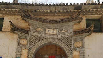 Un edificio tradicional con techo de tejas, un arco de entrada ornamentado y una puerta de madera.