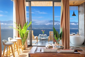 A modern interior with a large window overlooking a body of water and mountains.