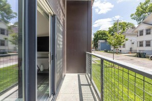 A residential building with a balcony, a garage door, and a street view. - Landing | Spectacular 2BD, Courtyard, Clubhouse (Dayton)