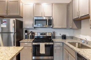Una cocina moderna con electrodomésticos de acero inoxidable, encimeras de granito y armarios de madera.