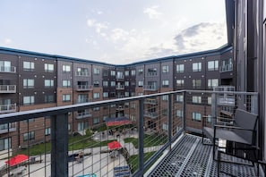 A multi-story residential building with balconies, a courtyard, and outdoor seating areas.