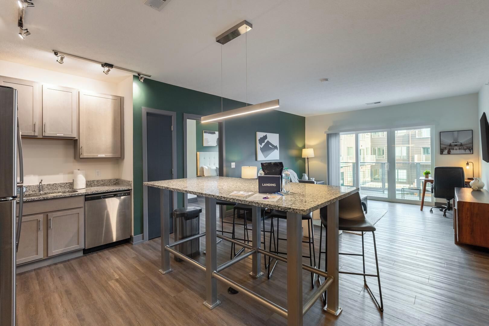Una cocina moderna con encimera de granito, electrodomésticos de acero inoxidable y una zona de bar con taburetes.