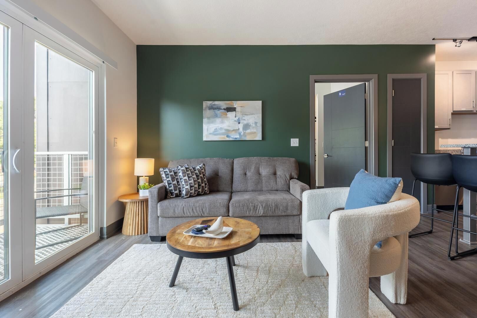 A living room with a grey sofa, a round coffee table, and a white armchair.