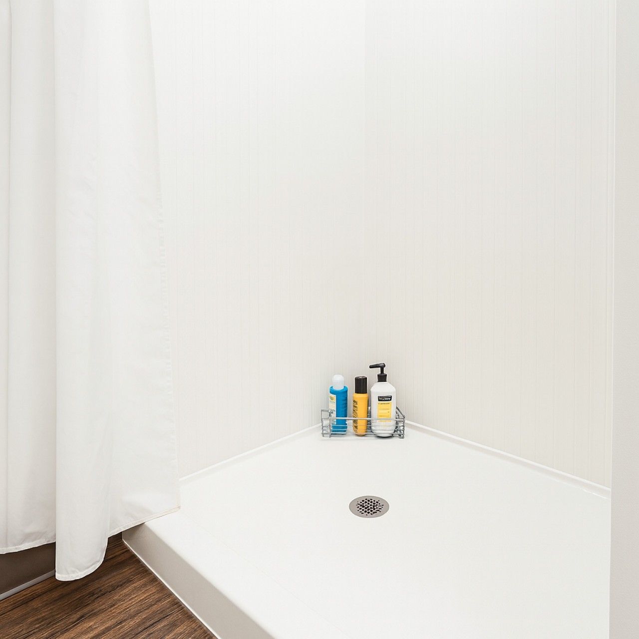 Ein Badezimmer mit einer weißen Badewanne, einer Duschvorhang und einem Ablagefach mit Pflegeprodukten.