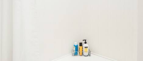 Ein Badezimmer mit einer weißen Badewanne, einer Duschvorhang und einem Ablagefach mit Pflegeprodukten.