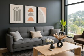 Ein modernes Wohnzimmer mit einem grauen Sofa, einem Couchtisch und Kunstwerken an der Wand.