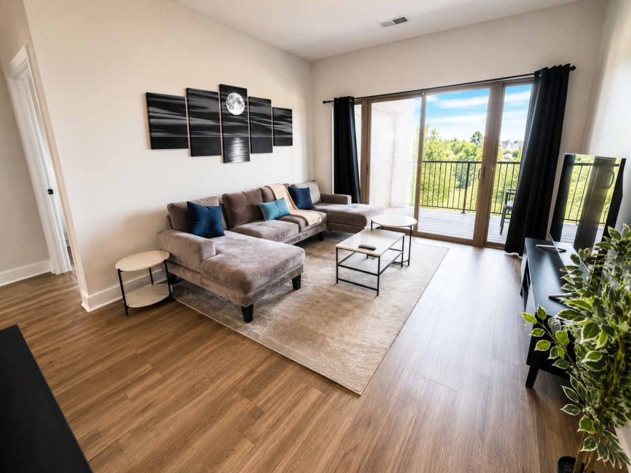 A modern living room with a sofa set, coffee table, and a large window with a balcony.