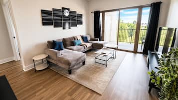A modern living room with a sofa set, coffee table, and a large window with a balcony.