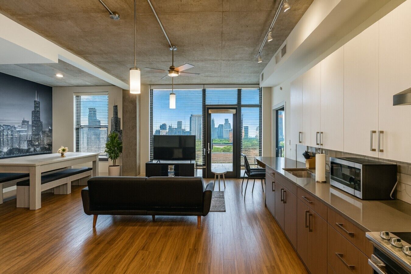 A modern living space with a cityscape view, a dining area, and a kitchen with stainless steel appliances.