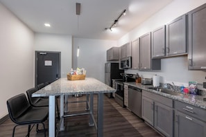 A modern kitchen with granite countertops, stainless steel appliances, and grey cabinetry. - Landing | Spectacular 2BD, Courtyard, Clubhouse (Dayton)