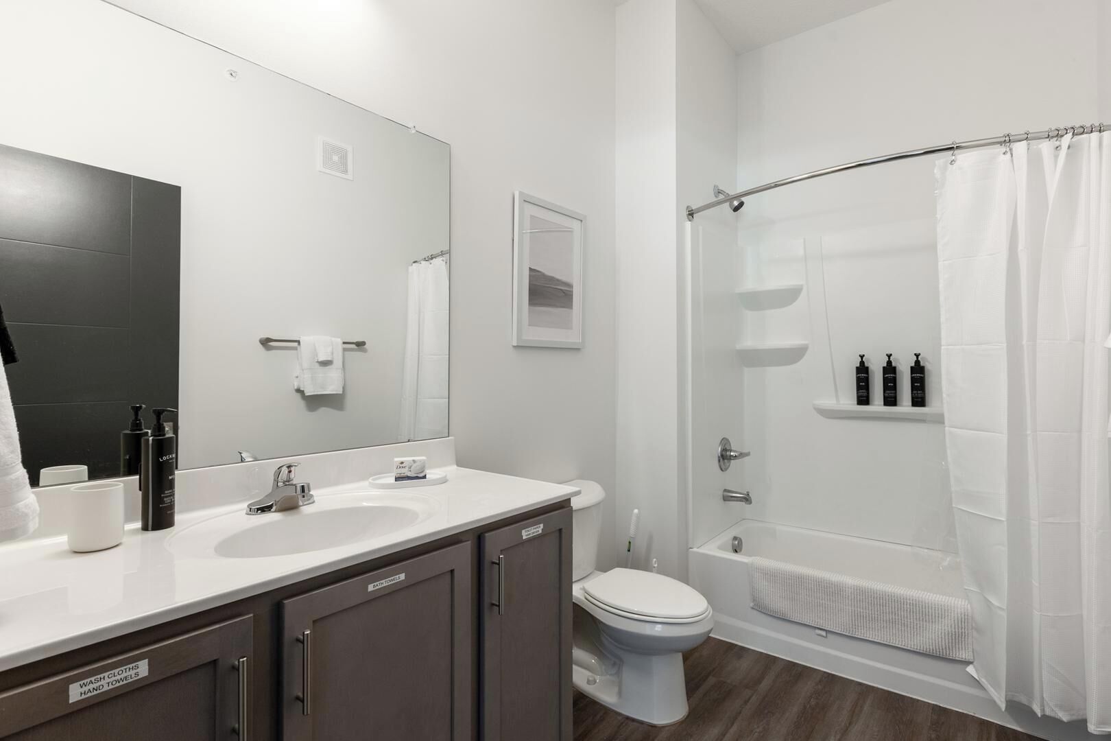 A modern bathroom with a large mirror, a sink, a toilet, and a shower area.