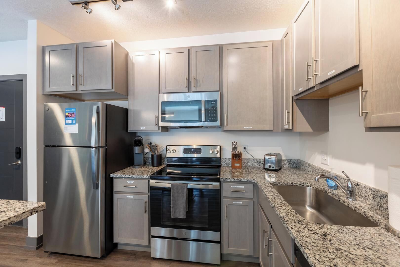 Una cocina moderna con electrodomésticos de acero inoxidable, encimeras de granito y armarios de madera clara.